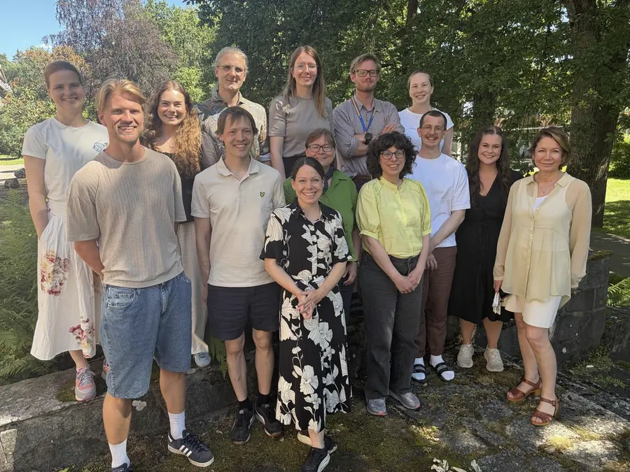 The Theragnostic Imaging research group photographed together outdoors on a summer day, standing in front of trees and a low stone wall.