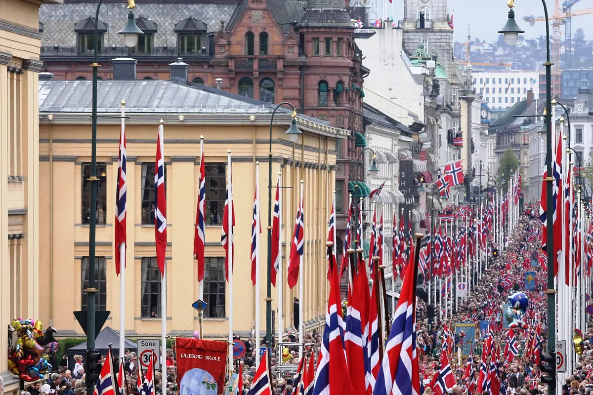 Karl Johans gate on 17 May, lined with Norwegian flags and packed with people following the parade past the old University of Oslo buildings.
